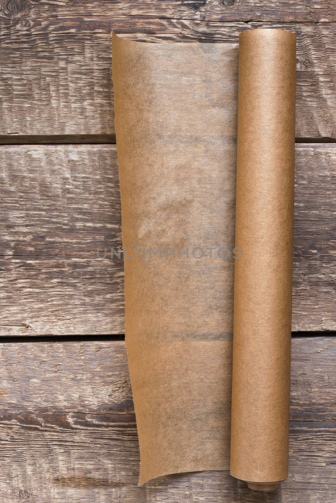 An open roll of paper on the wooden table background by Deniskarpenkov