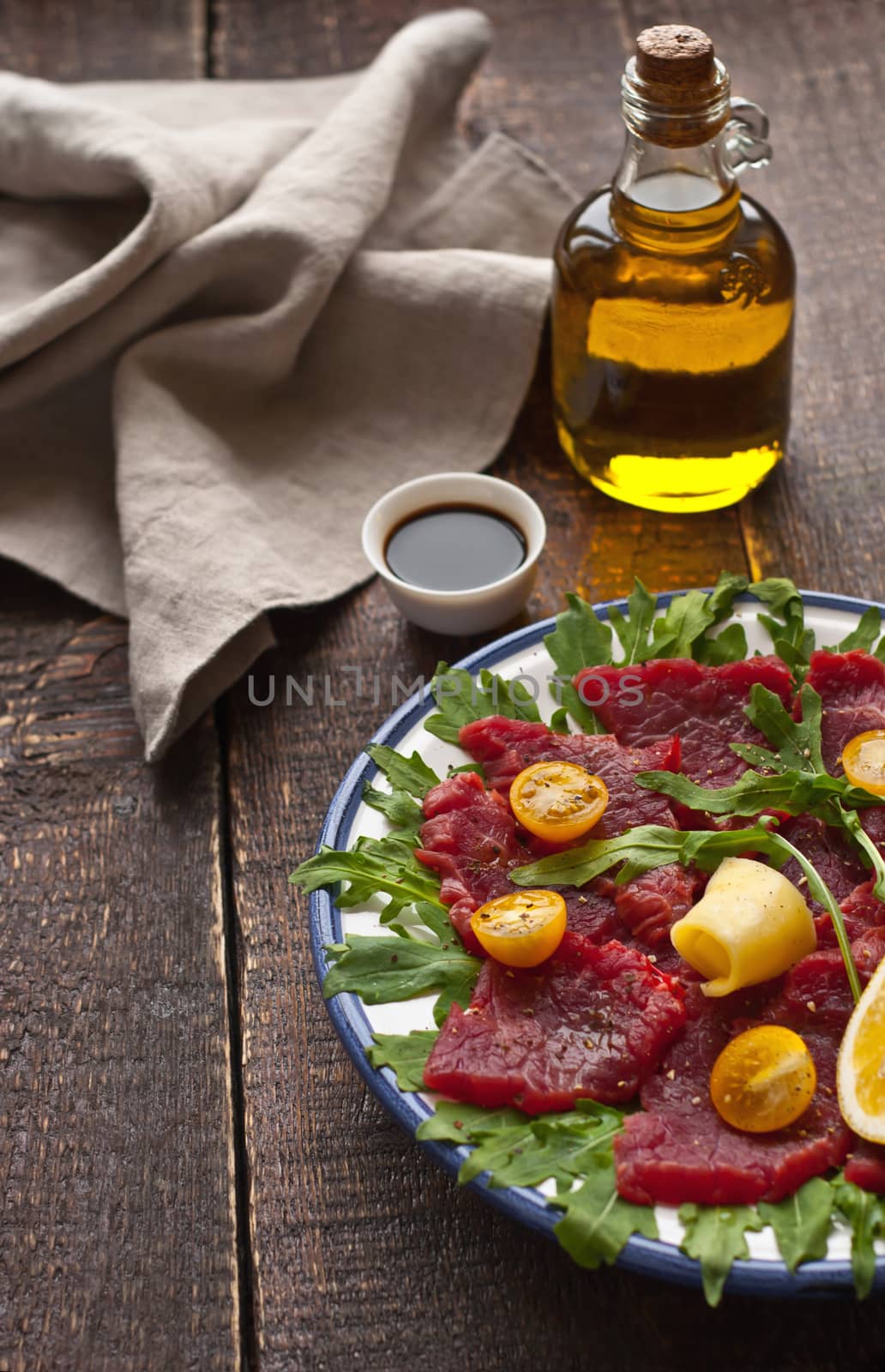 Carpaccio with arugula, tomatoes and cheese on the rustic table