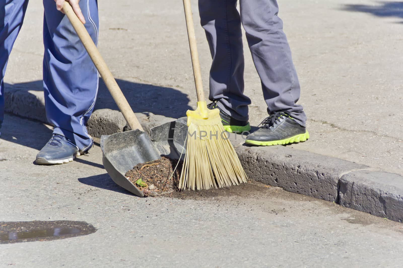 Photo of two men legs cleaning street with broom and shovel