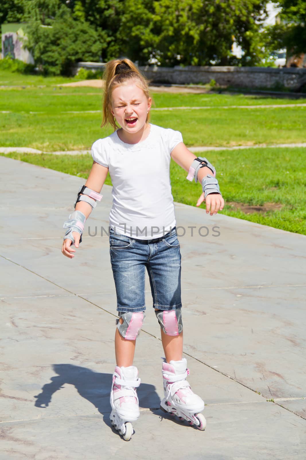 Learning girl on roller skates in summer