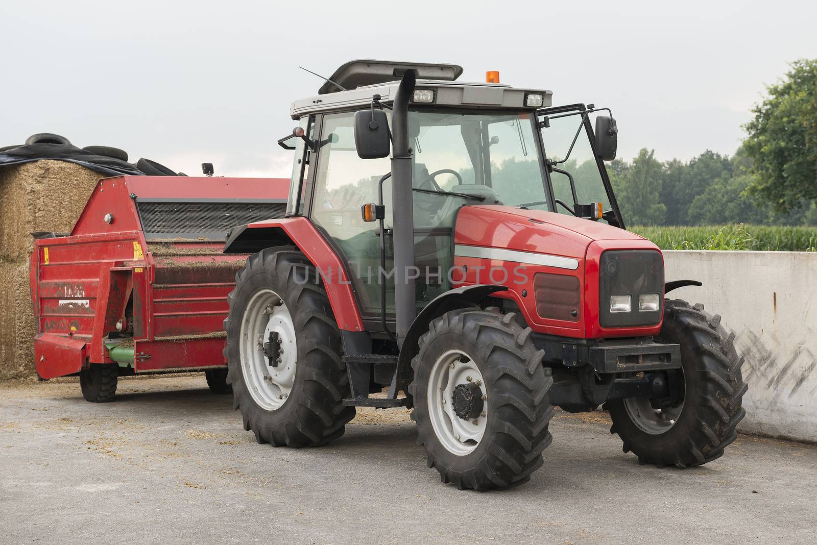 Red tractor with red cattle feed diffuser on a dairy farm
