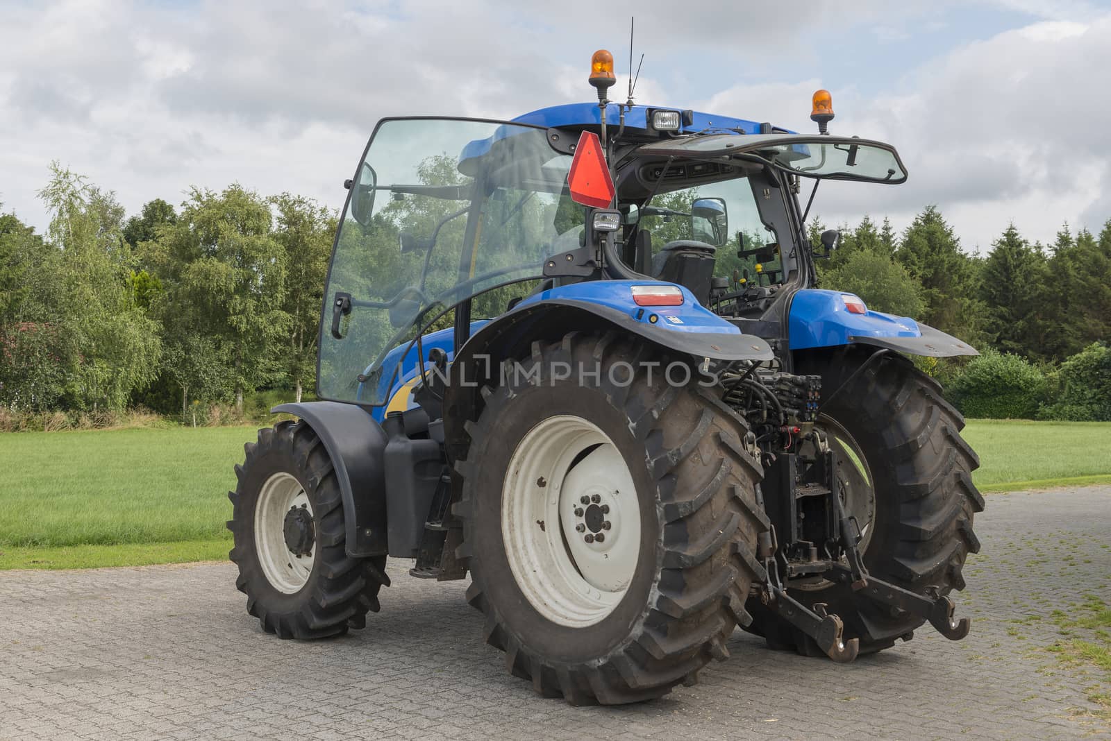Modern blue tractor on a paved farmyard
