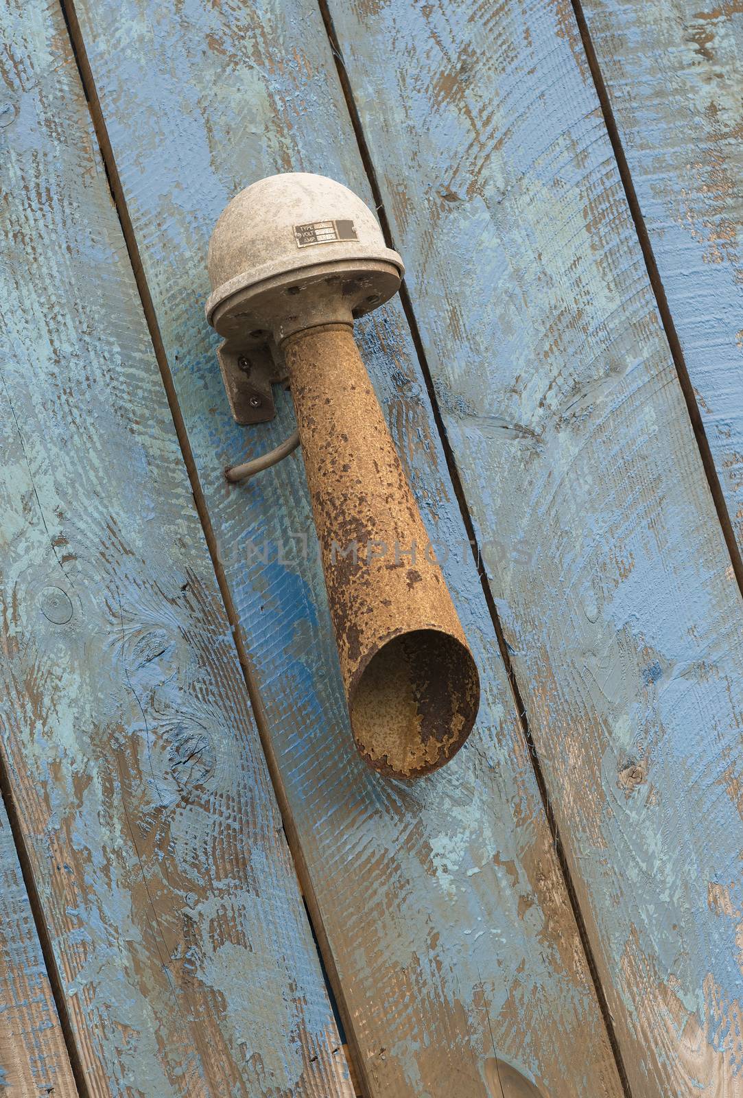 Old rusted sound horn on a blue weathered wooden background
