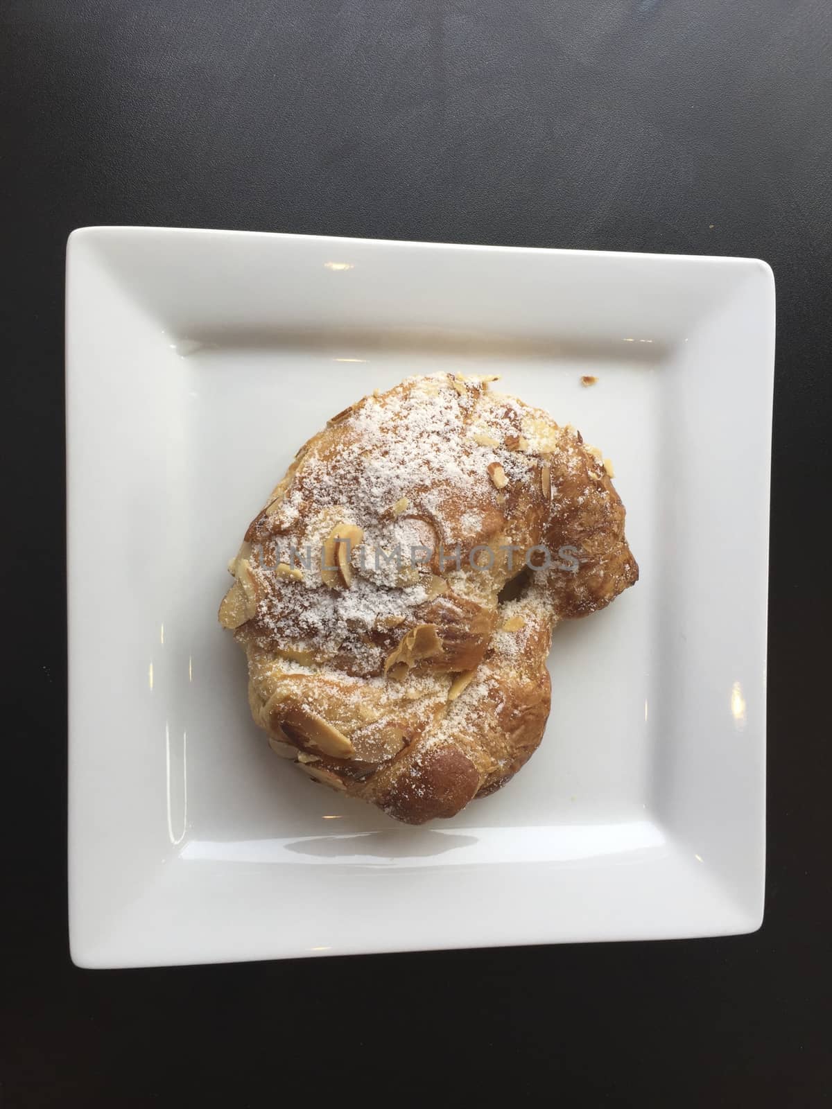 Pastry with nuts on a white plate, sweet croissant.