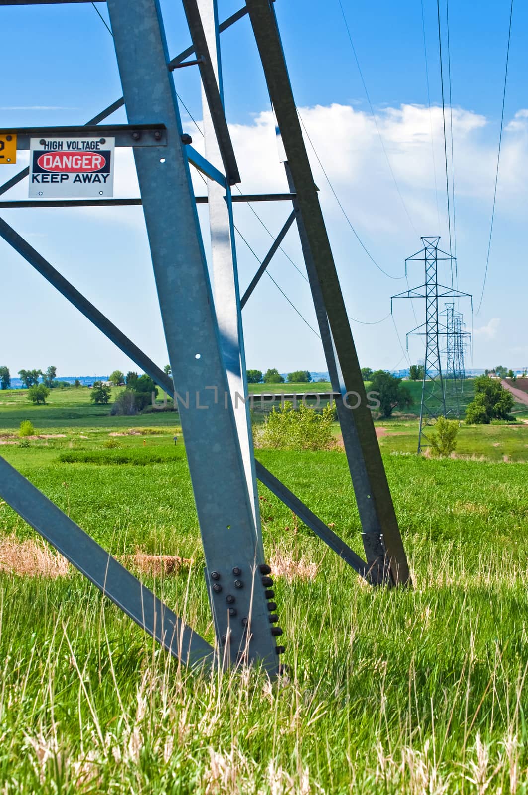 High Voltage transmission tower with a warning sign on it.