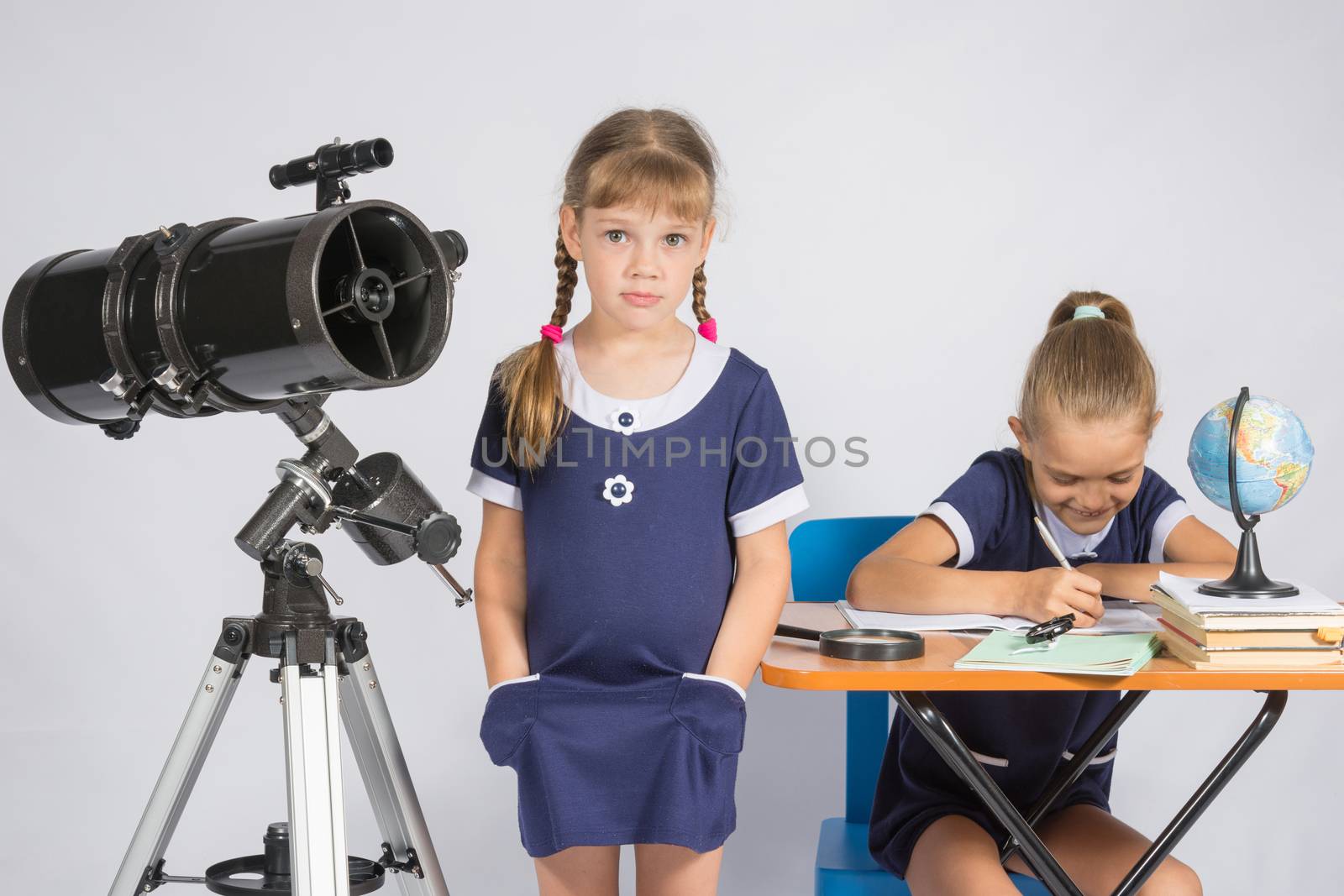 A girl stands at a telescope with his hands in his pockets, another girl having fun sitting at the table and writes by Madhourse
