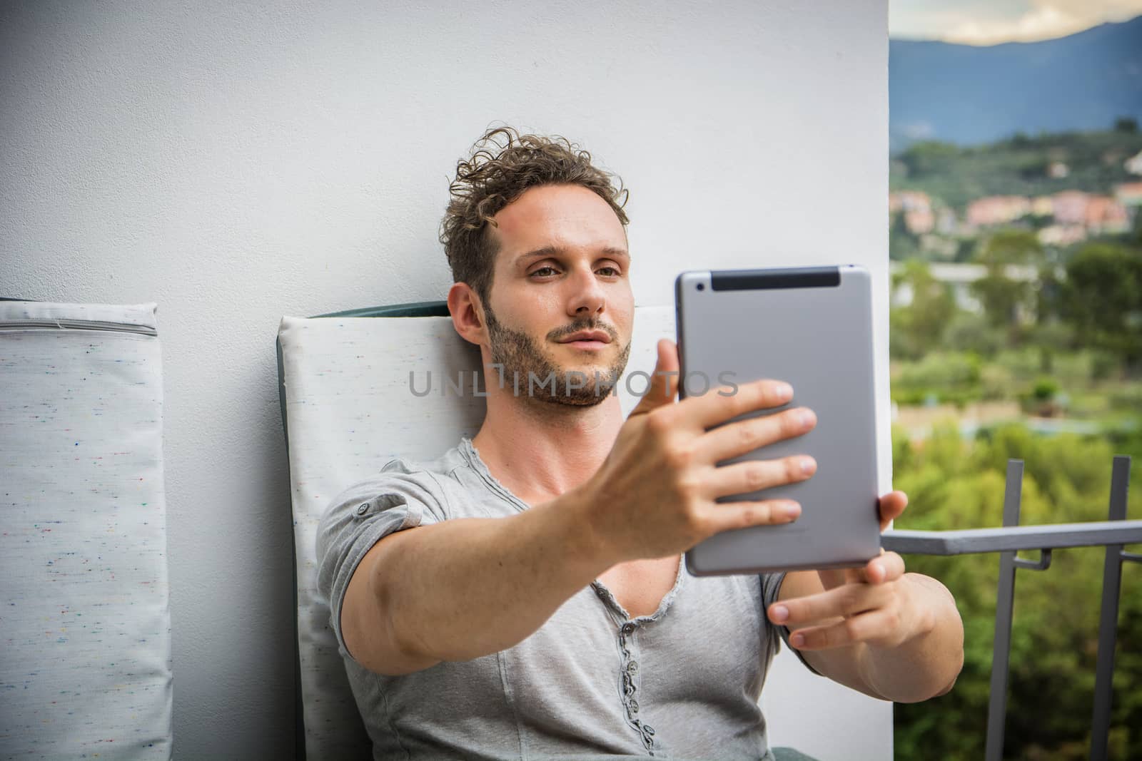 Handsome trendy man looking down at a tablet computer, outdoor by artofphoto