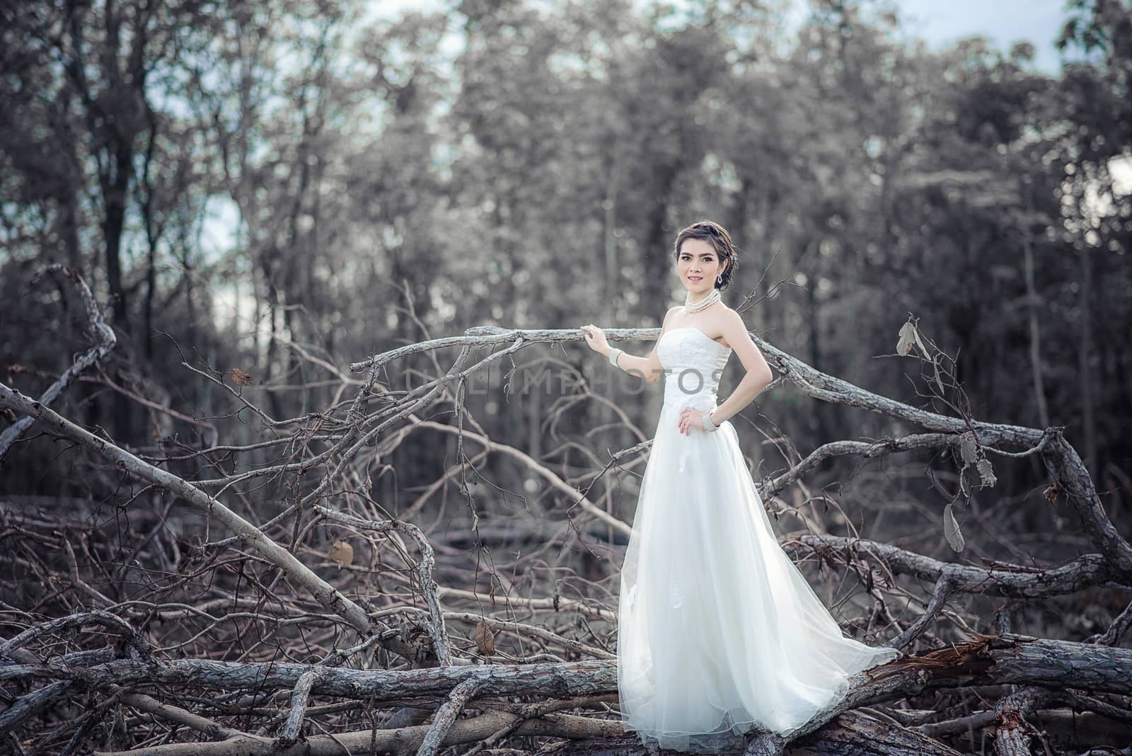 Beautiful girl in the dress of the bride walks in autumn park with trees and fallen leaves