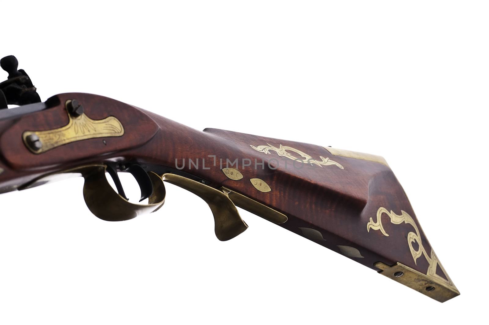 Close up view of a flint lock rifle and the brass inlays and engravings on the stock.