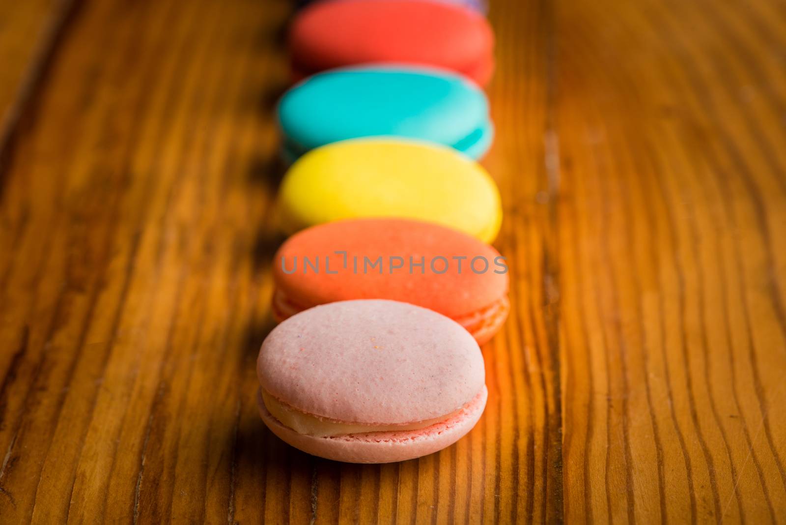 A row of colorful  macaroons on wooden table