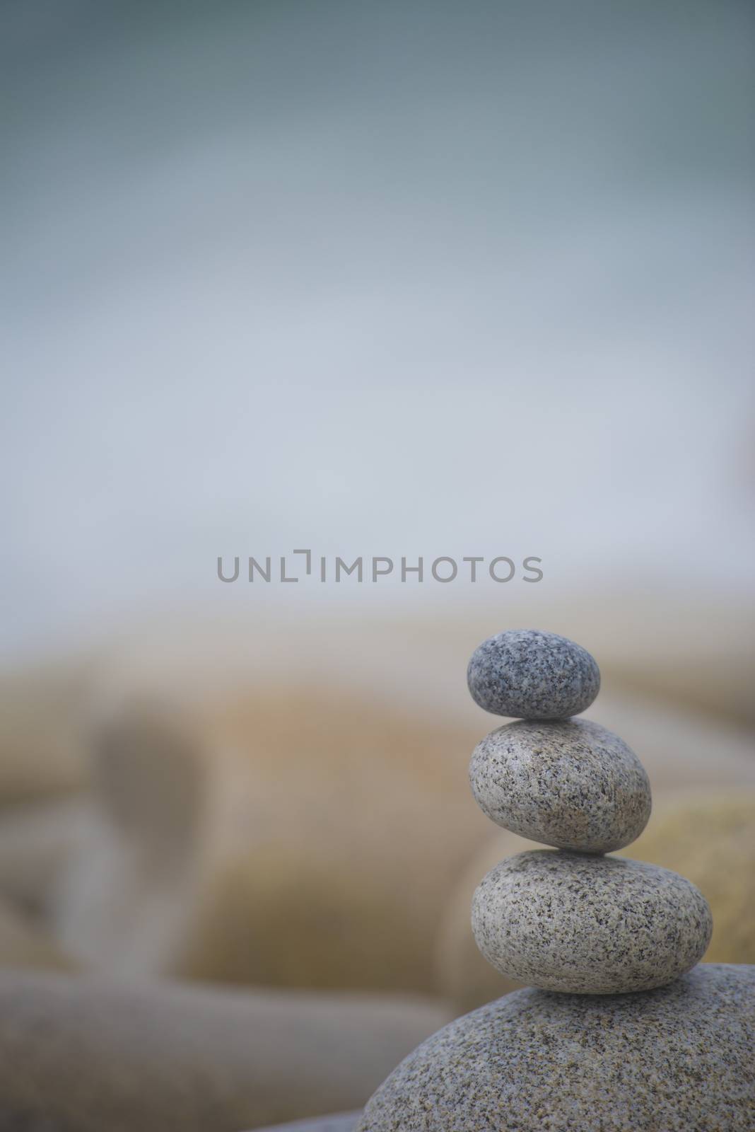 Three pebbles stack over natural background with free space for text, Zen and harmony concept. Vertical image.
