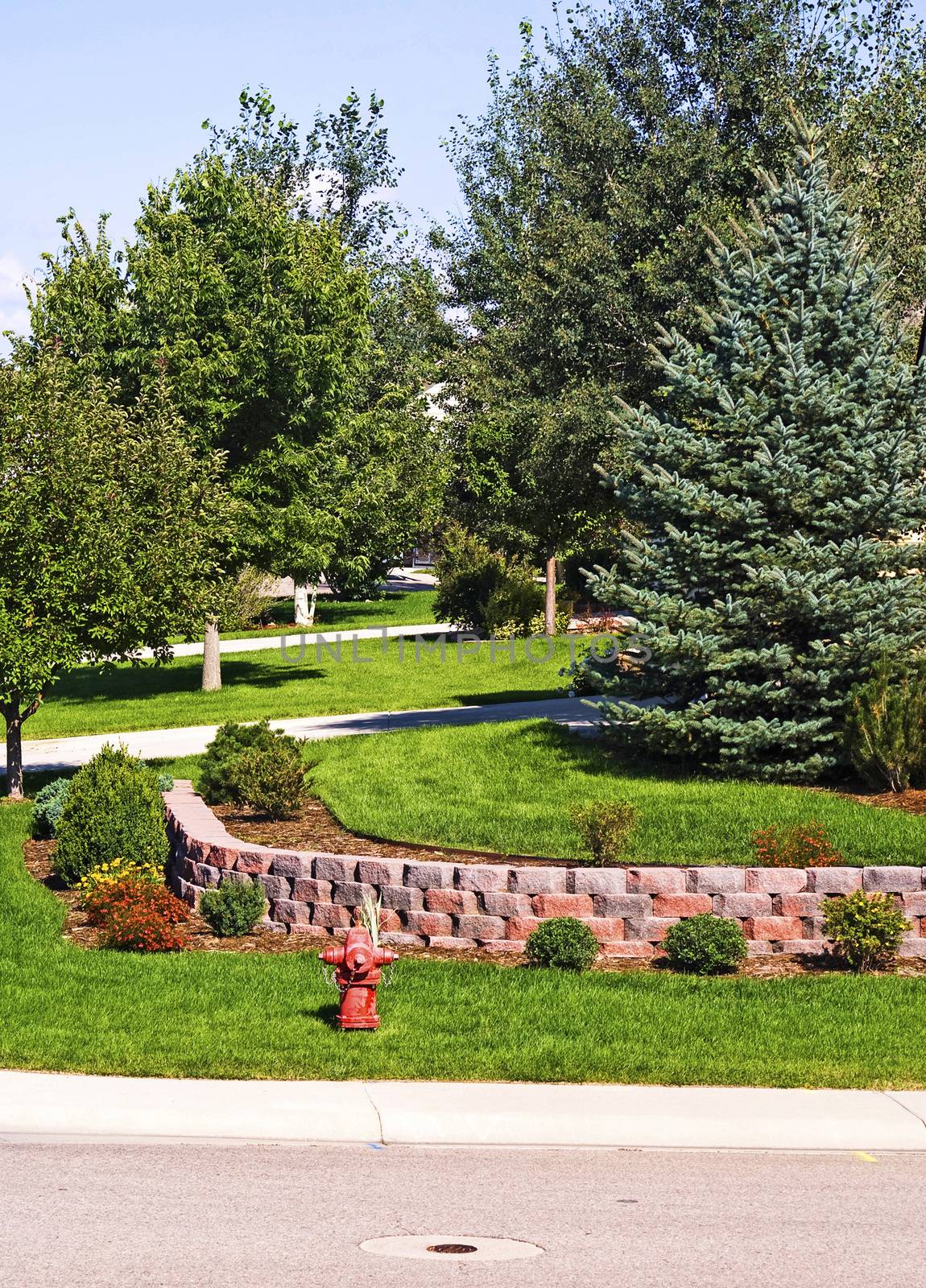 Well manicured yard with a retaining wall on a corner lot located in a suburban neighborhood.