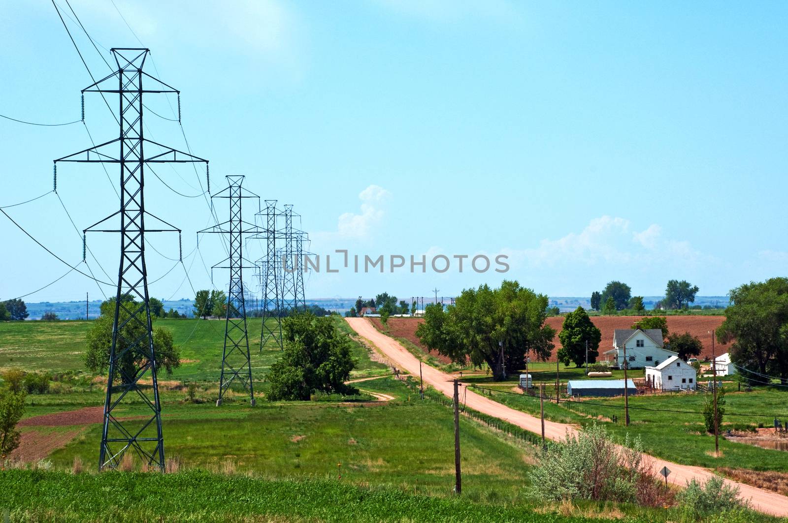 Steel power poles carry electricity through the rural landscape towards a large city.