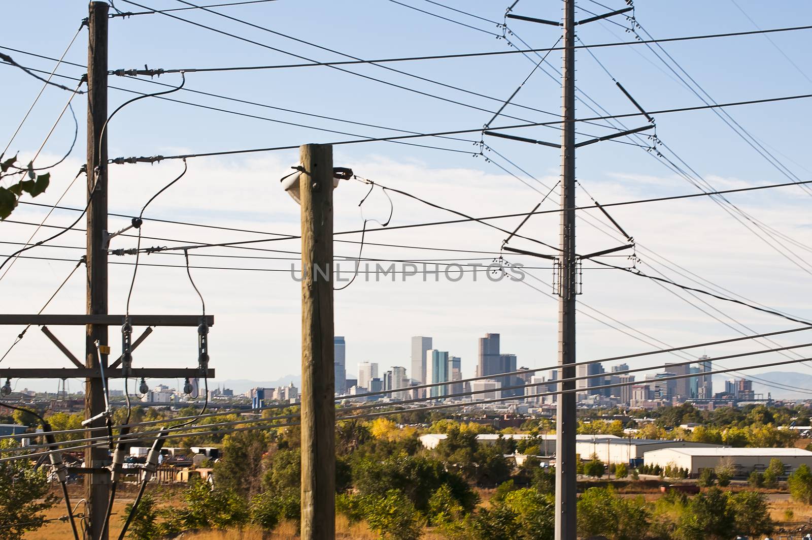 Cluttered power poles and lines in front of view of downtown Denver, Colorado, USA.