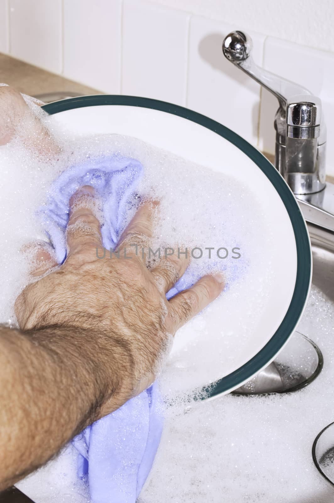 Washing dishes in the sink by hand.
