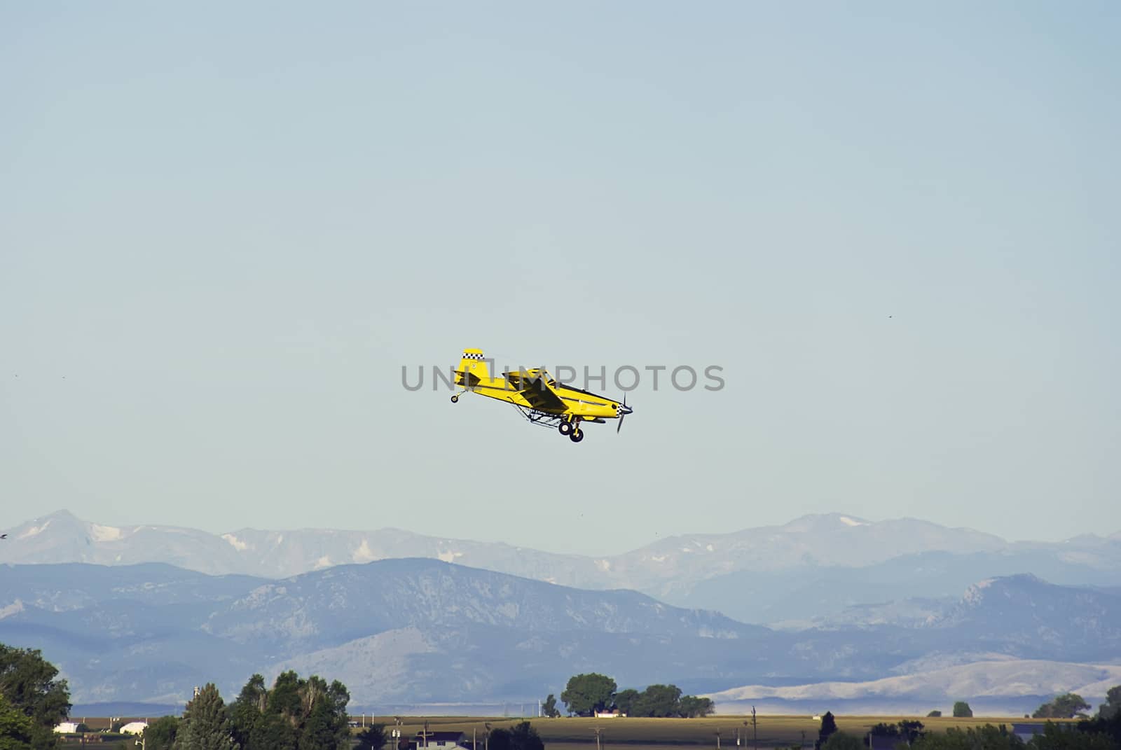 Airplane against the Rocky mtns making another run at a cornfield.