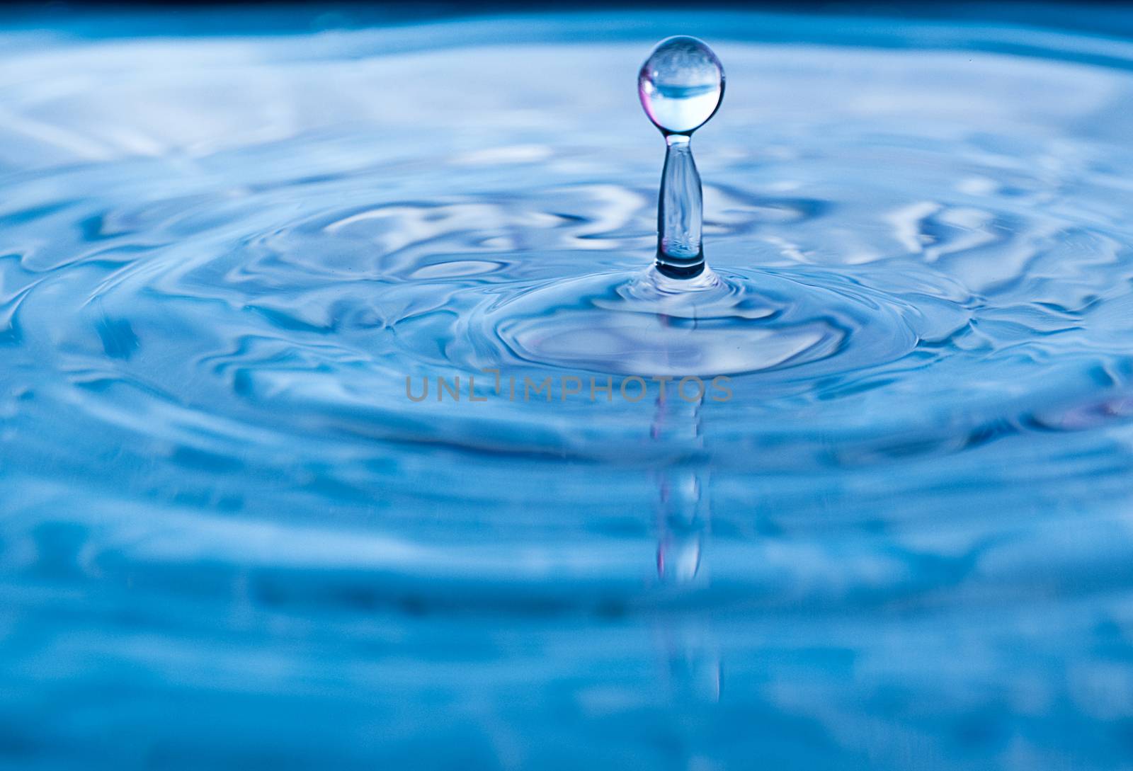 Stop action of water droplet with red reflection in the water