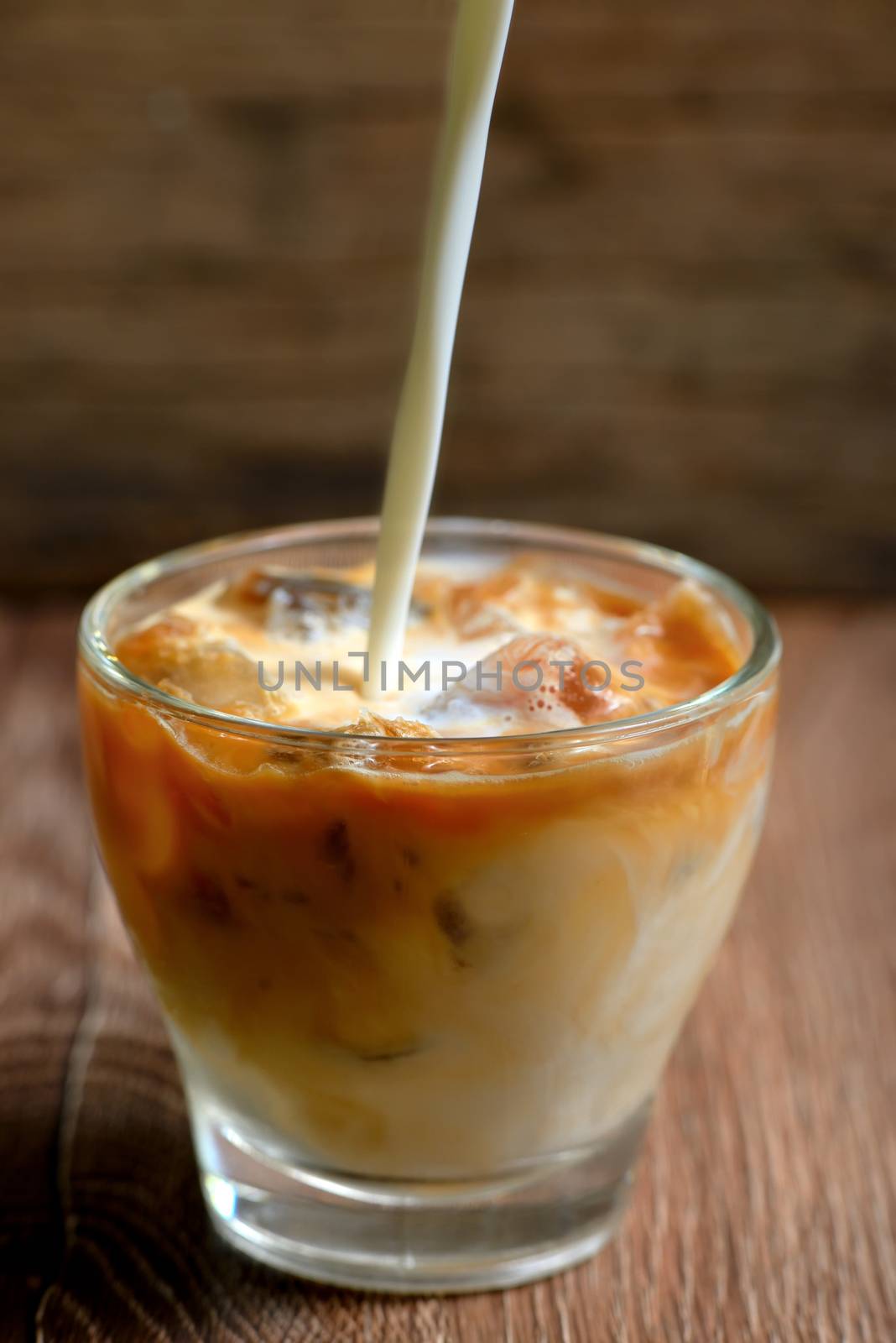 Iced coffee with milk on wooden table