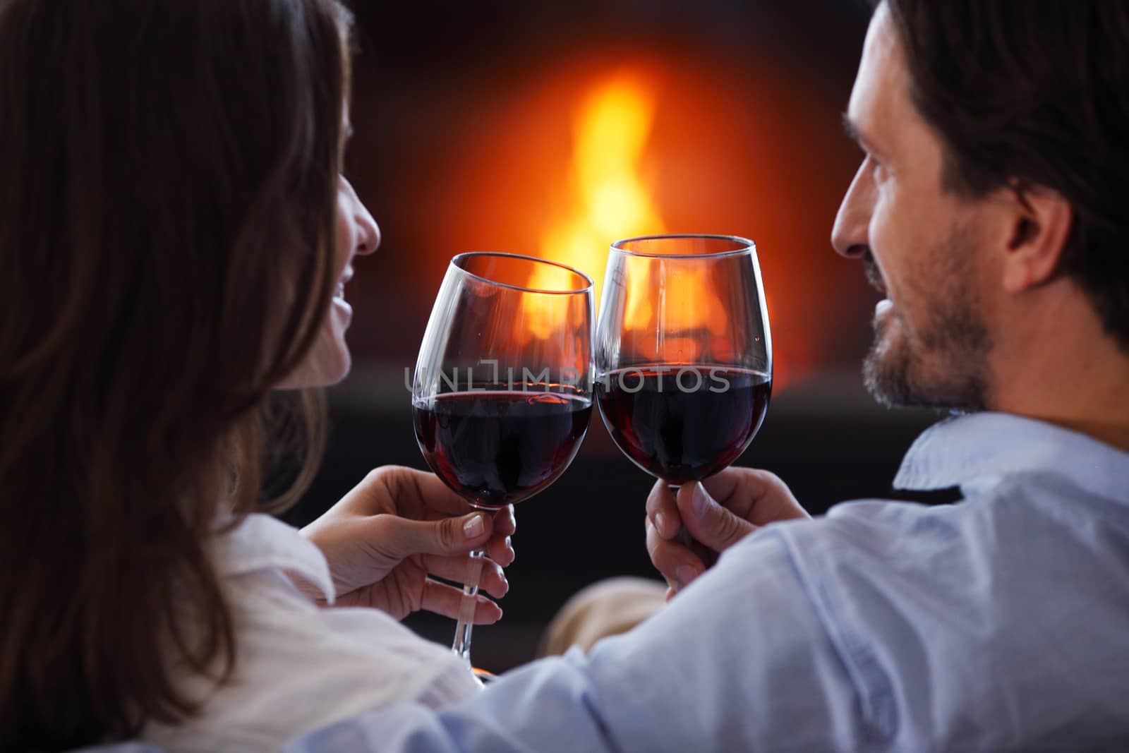 Romantic couple drinking wine at home near fireplace