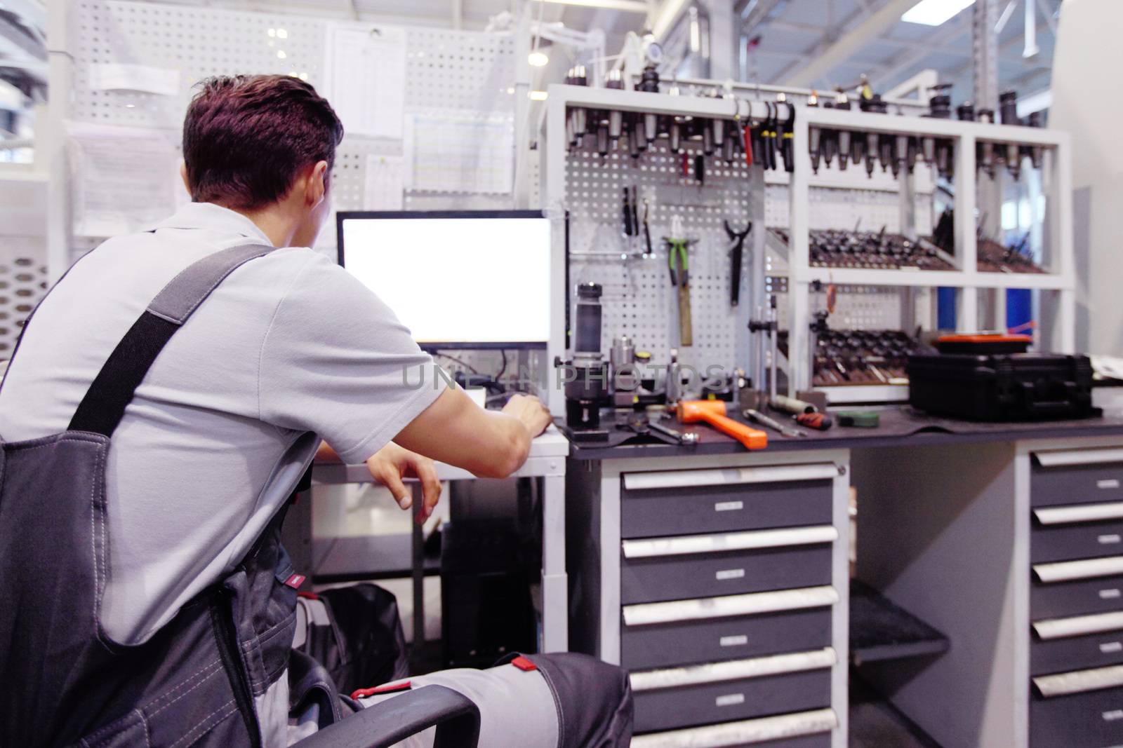 Worker at workplace with computer and tools at CNC factory