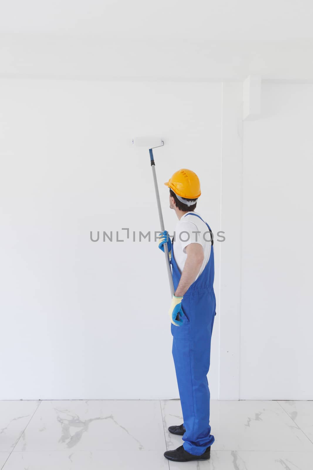 Young worker in hardhats painting the wall