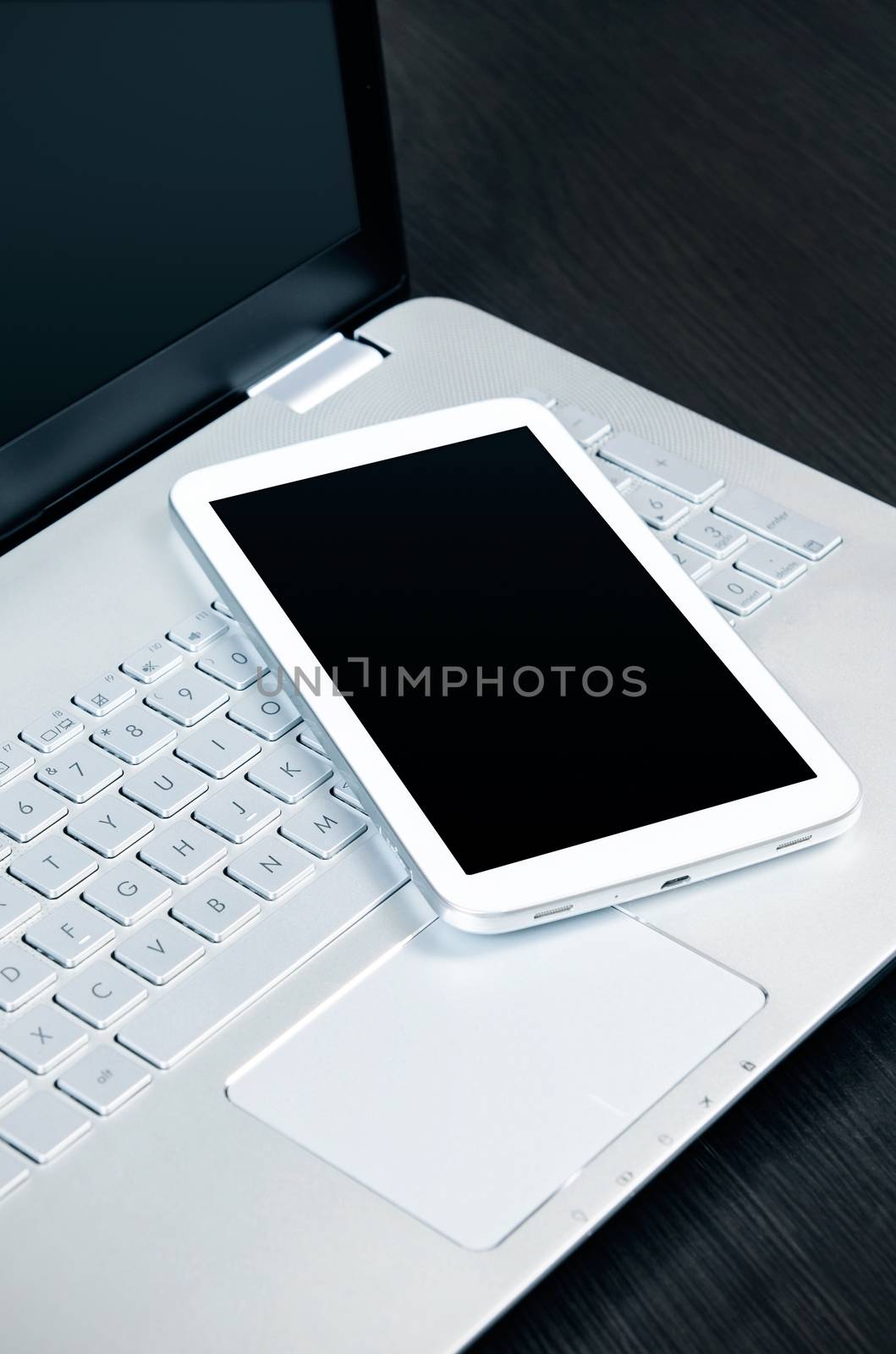 Laptop with white digital tablet on desk 