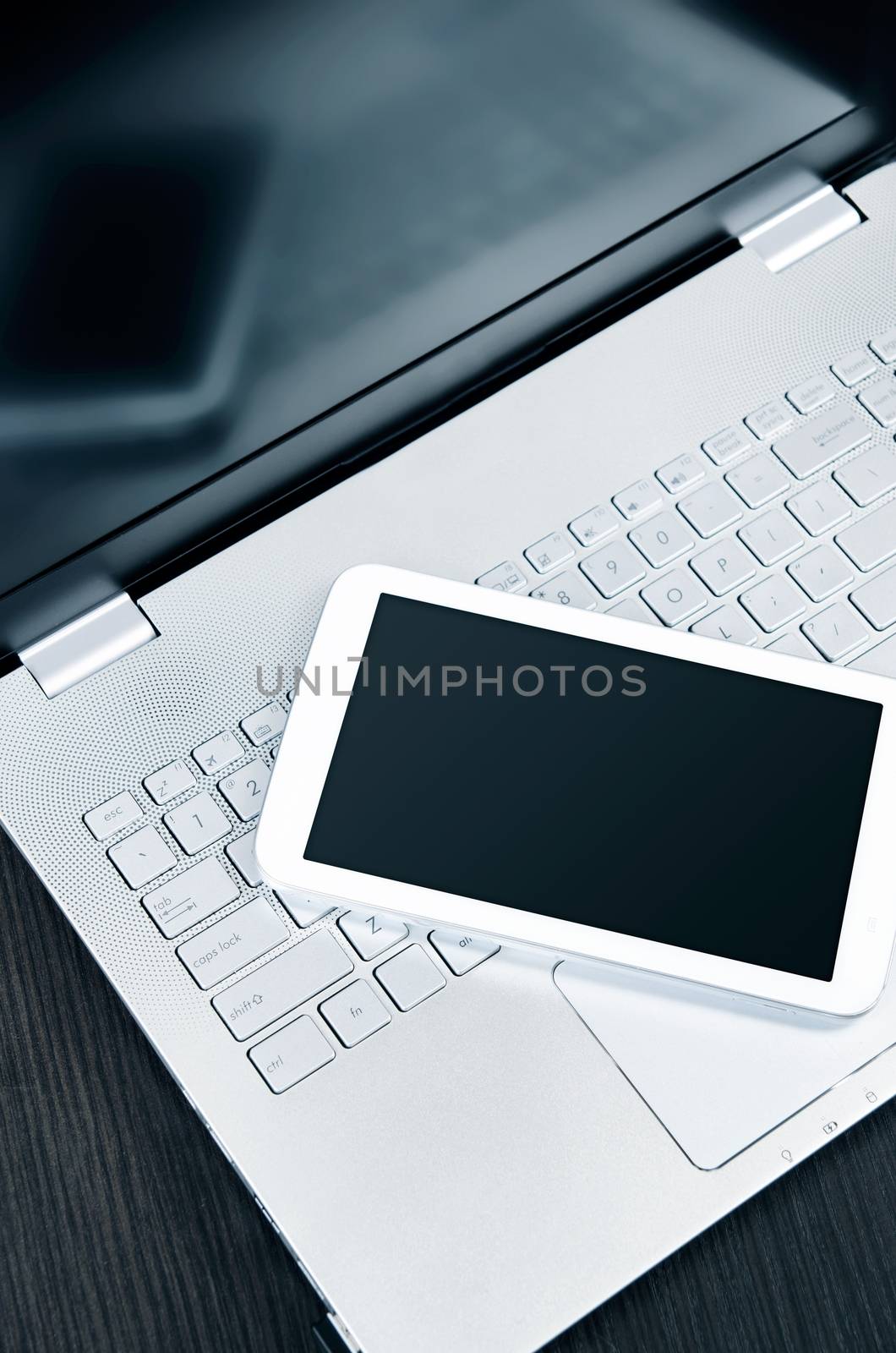 Laptop with white digital tablet on desk 