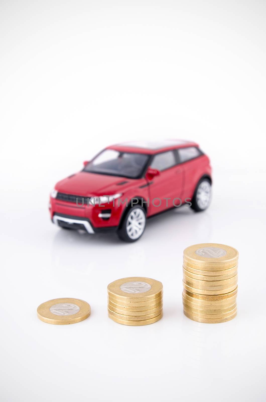 Saving money to buy a vehicle. Coins and car toy on white by simpson33