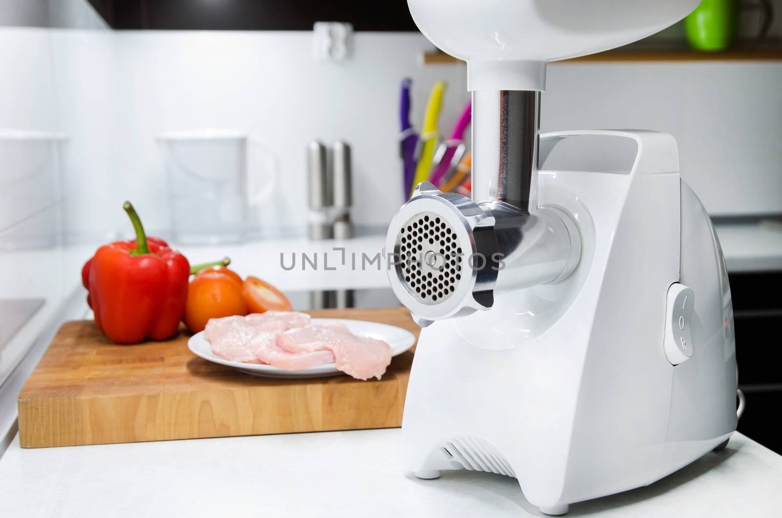 Meat grinder in modern kitchen. Vegetables in background by simpson33