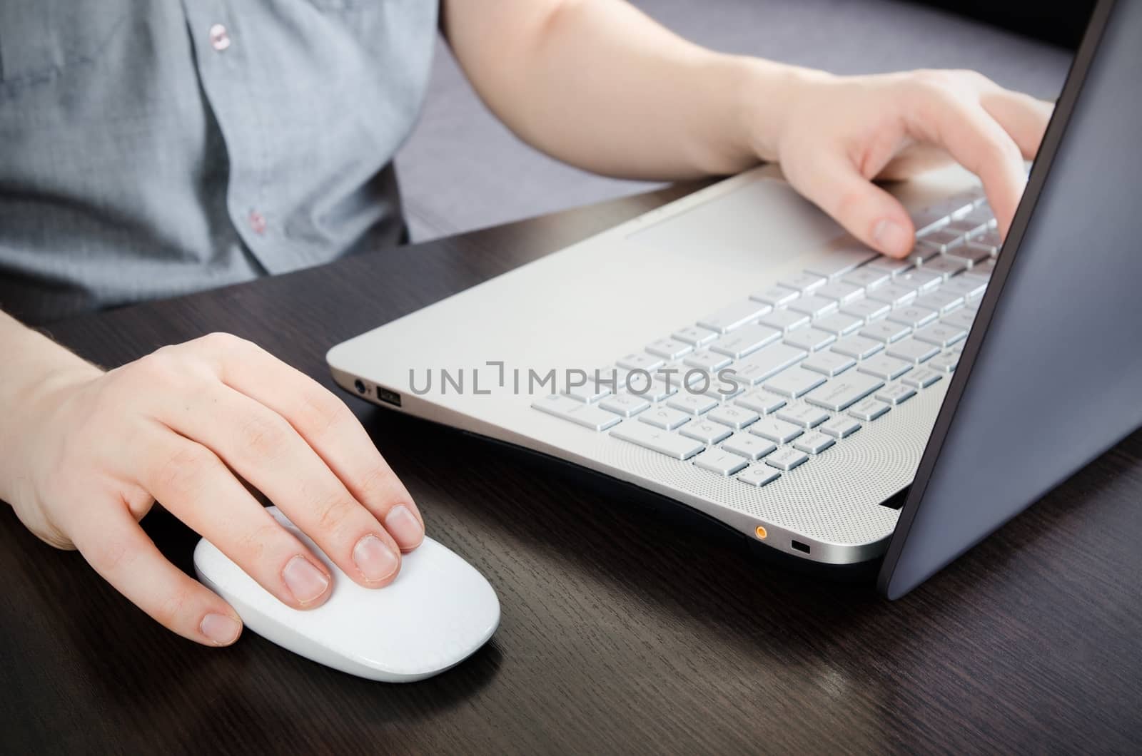 Man working in office. Laptop with white keyboard and white mouse