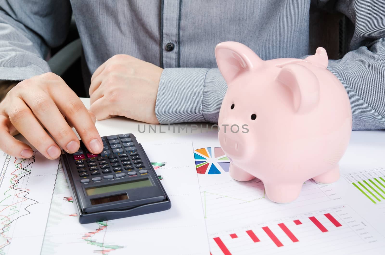 Man calculates money. Piggy bank and business documents on desk by simpson33