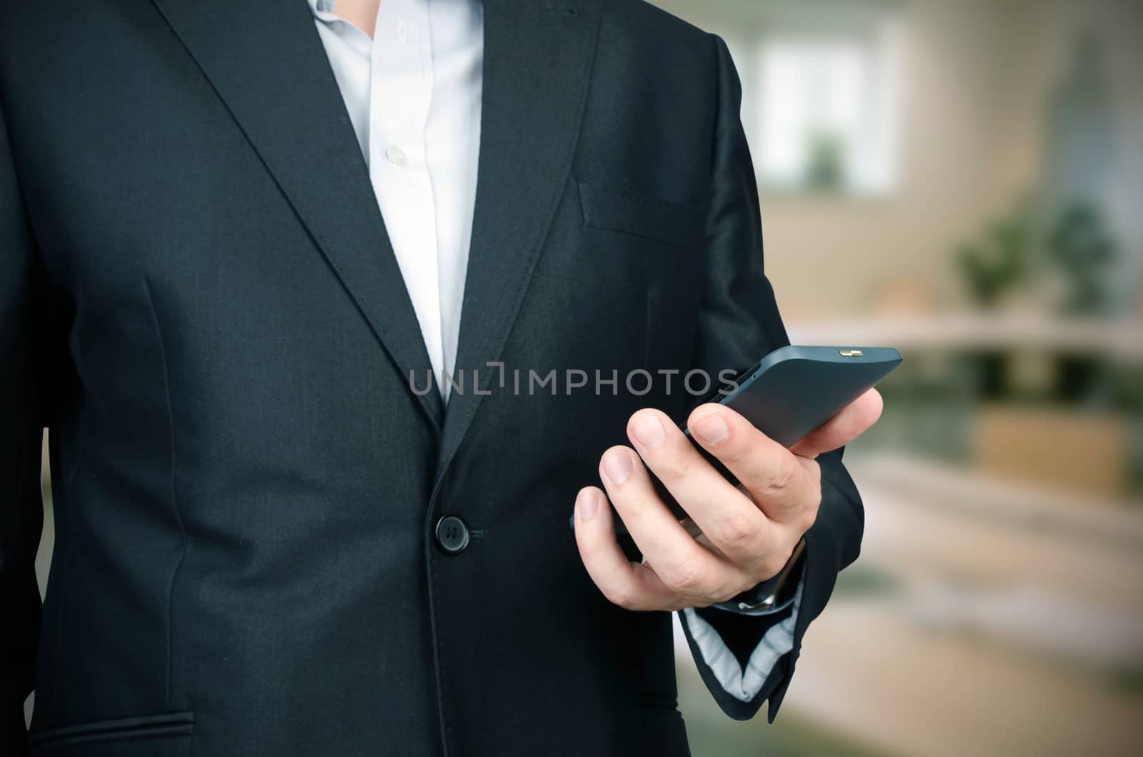 Business man in suit using smart phone in office