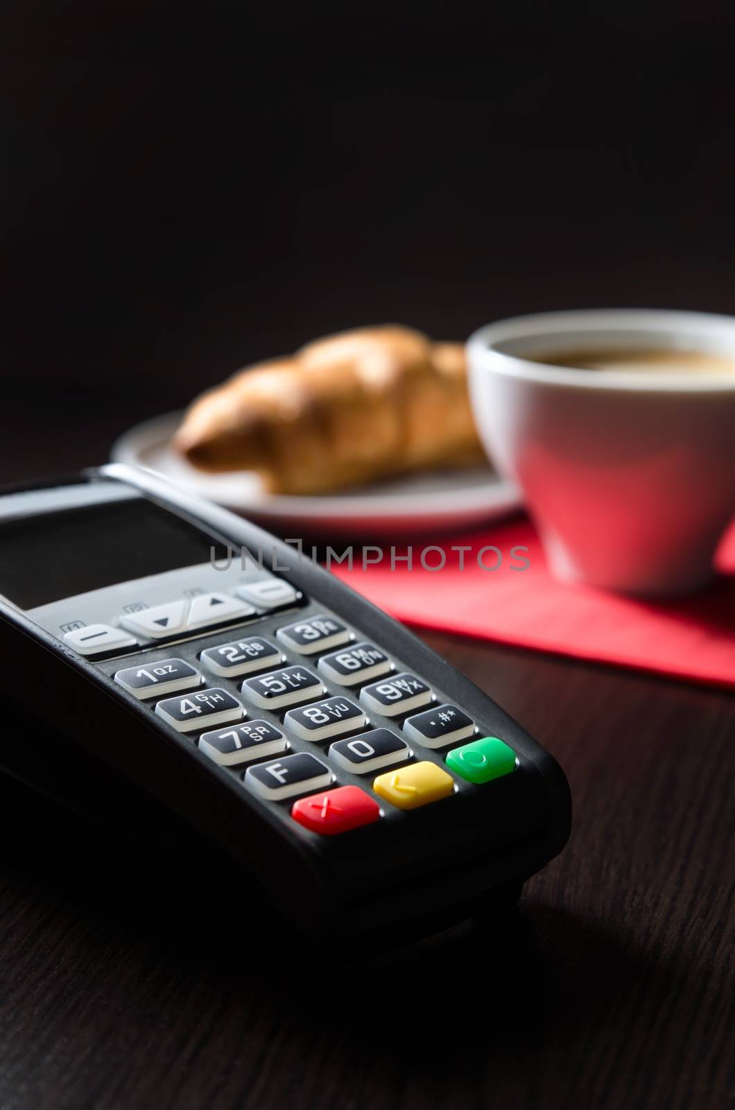 Payment terminal in restaurant. Croissaint and coffee in background