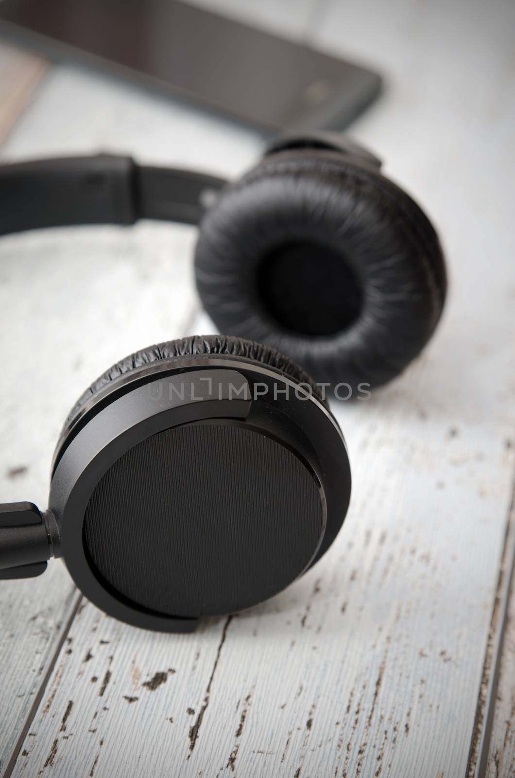 Wireless modern head phones and smart phone on wooden background