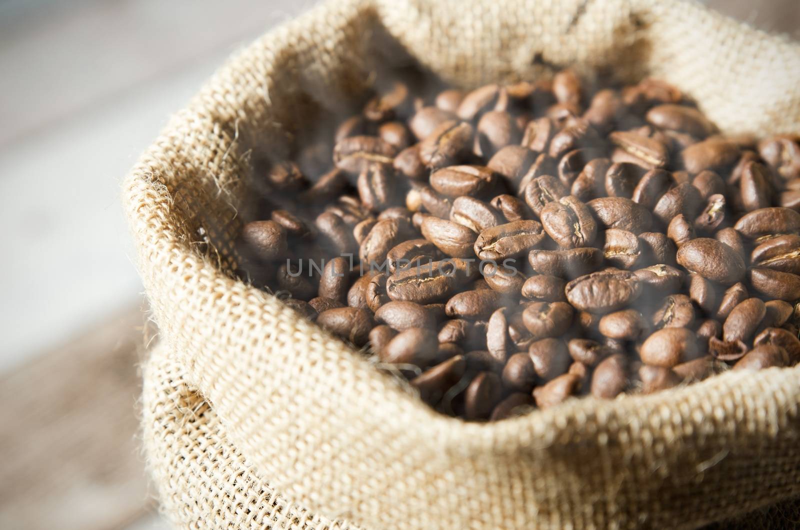 Close up coffee beans in jute bag on wooden table