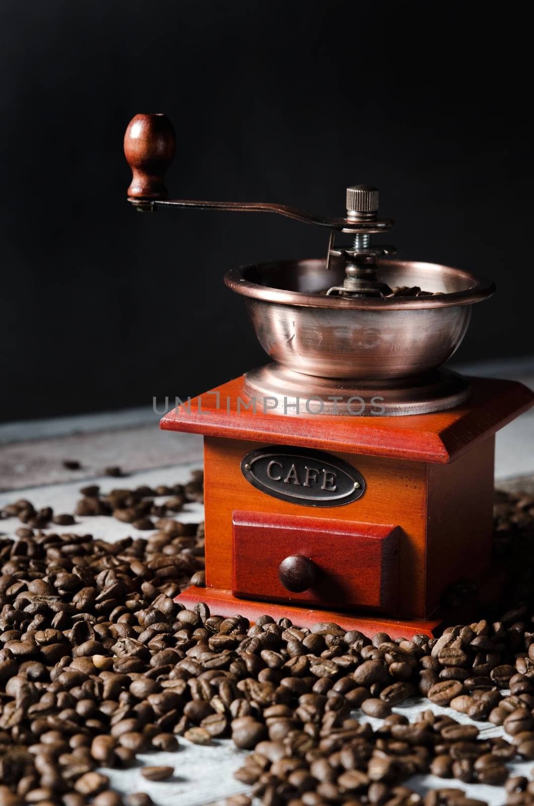 Old retro coffee grinder on wooden background with coffee beans by simpson33