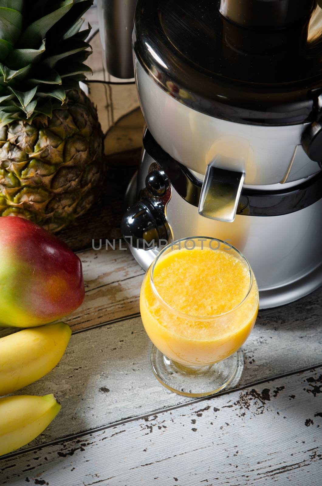 Fresh juice and juicer. Photo on wooden background with lot of fruits