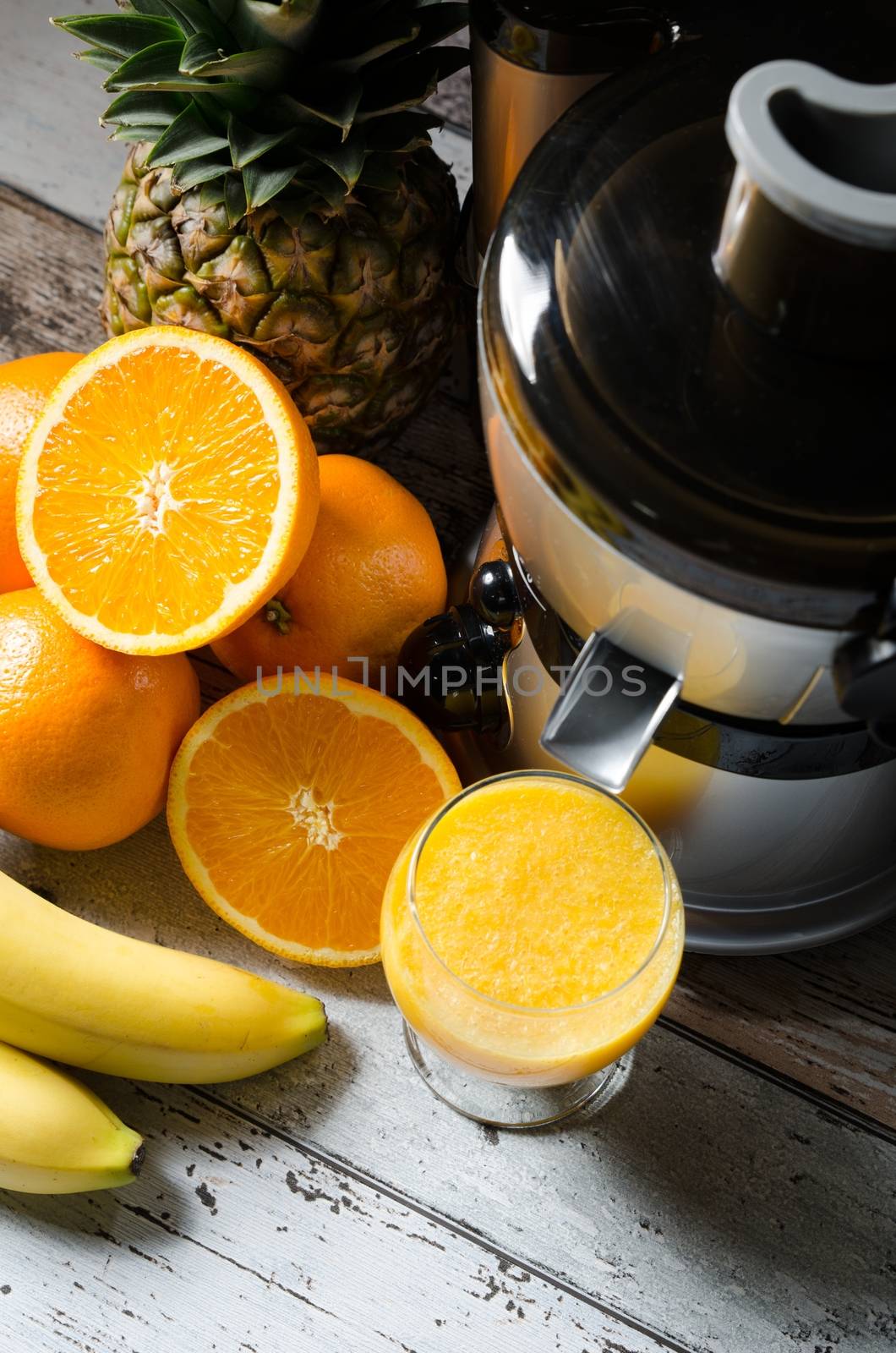 Fresh juice and juicer. Photo on wooden background with lot of fruits