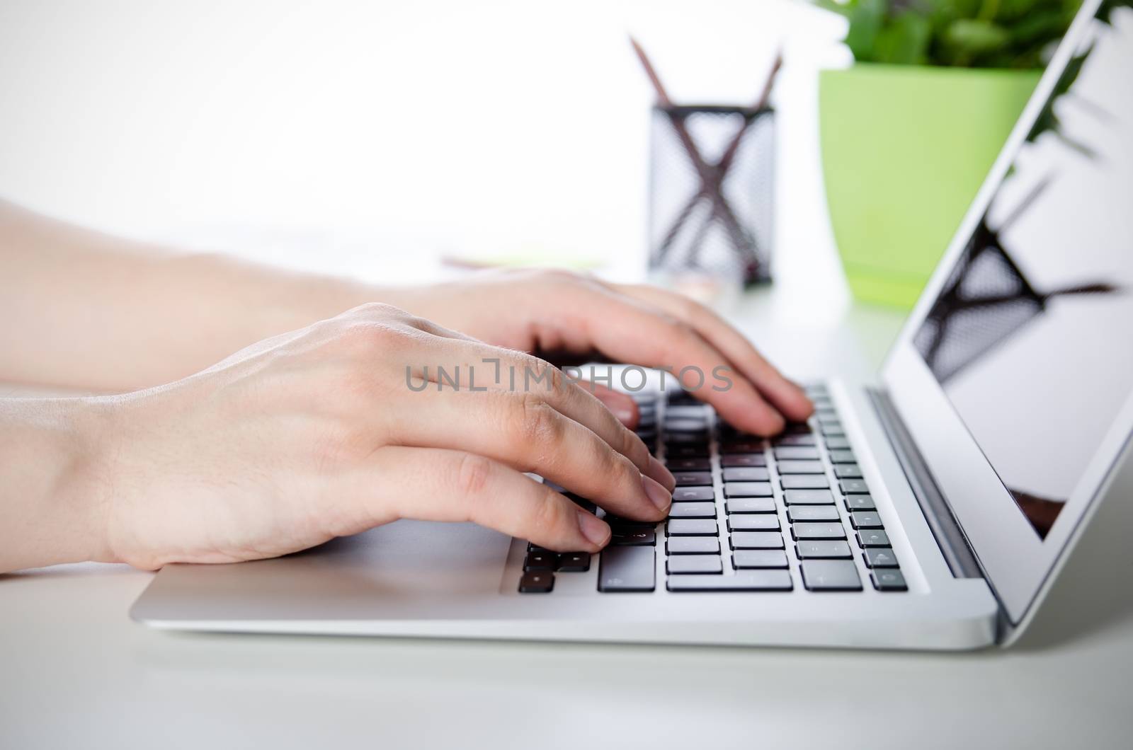 Man working with modern laptop in office. Hands typing on keyboard