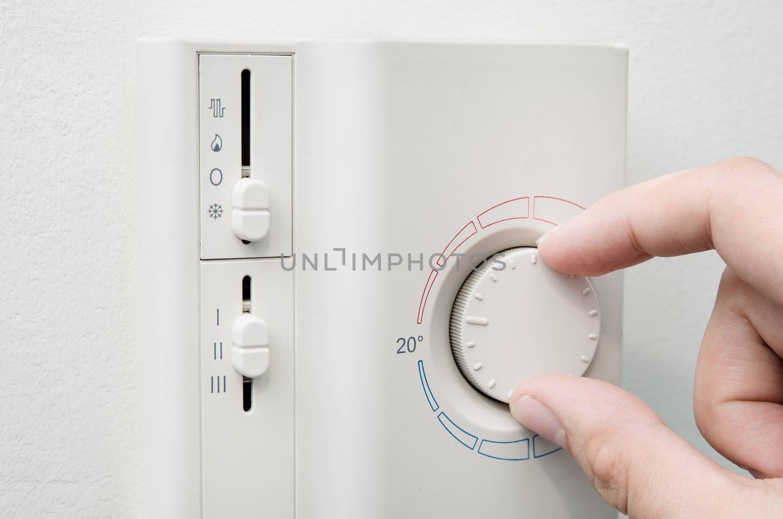 Hand switches air conditioner thermostat on wall by simpson33