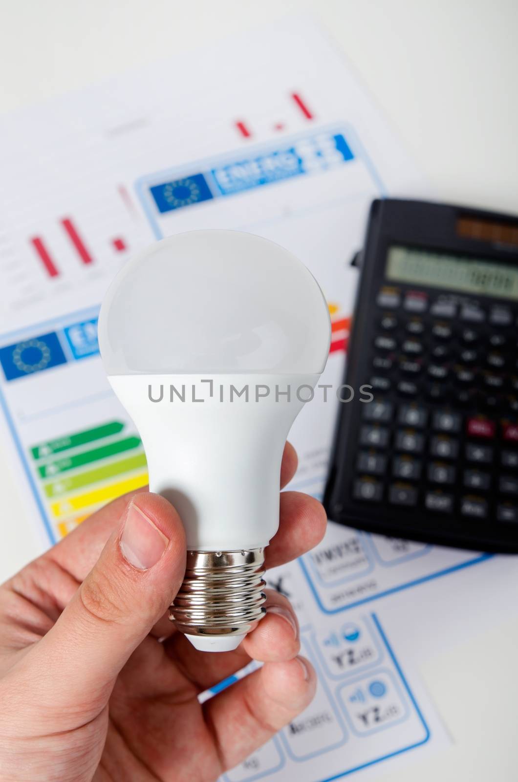 Hand holding LED bulb. Energy efficiency chart and calculator by simpson33