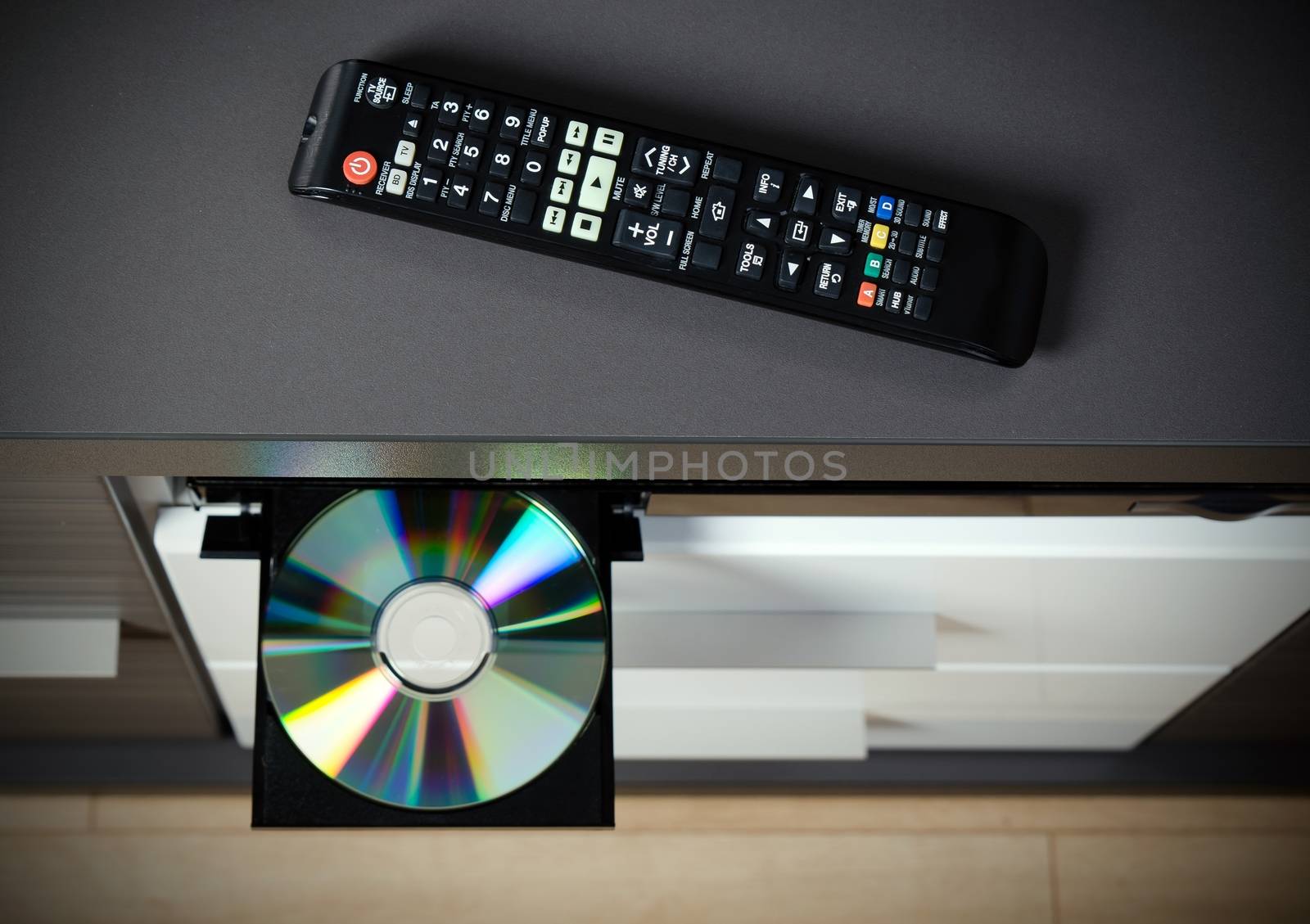 Remote control and Blu-ray or DVD player with inserted disc. 