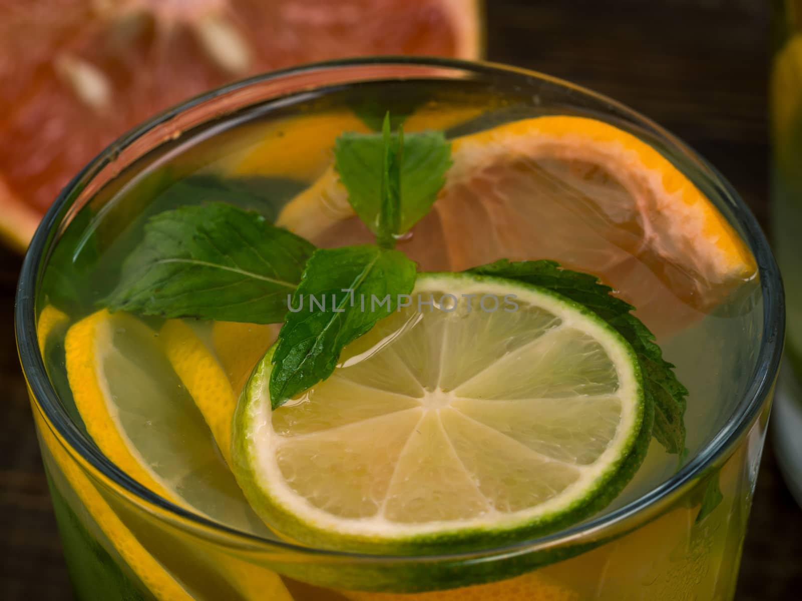 Close up cold homemade lemonade with fresh lemon, lime, grapefruit and mint. Summer drink on dark wooden background