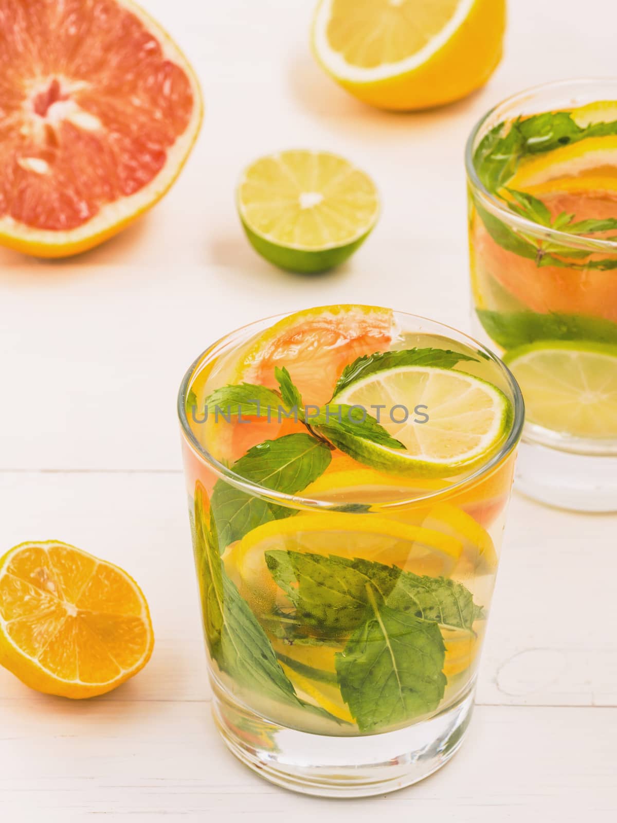 Cold homemade lemonade with fresh lemon, lime, grapefruit and mint. Summer drink on white wooden background