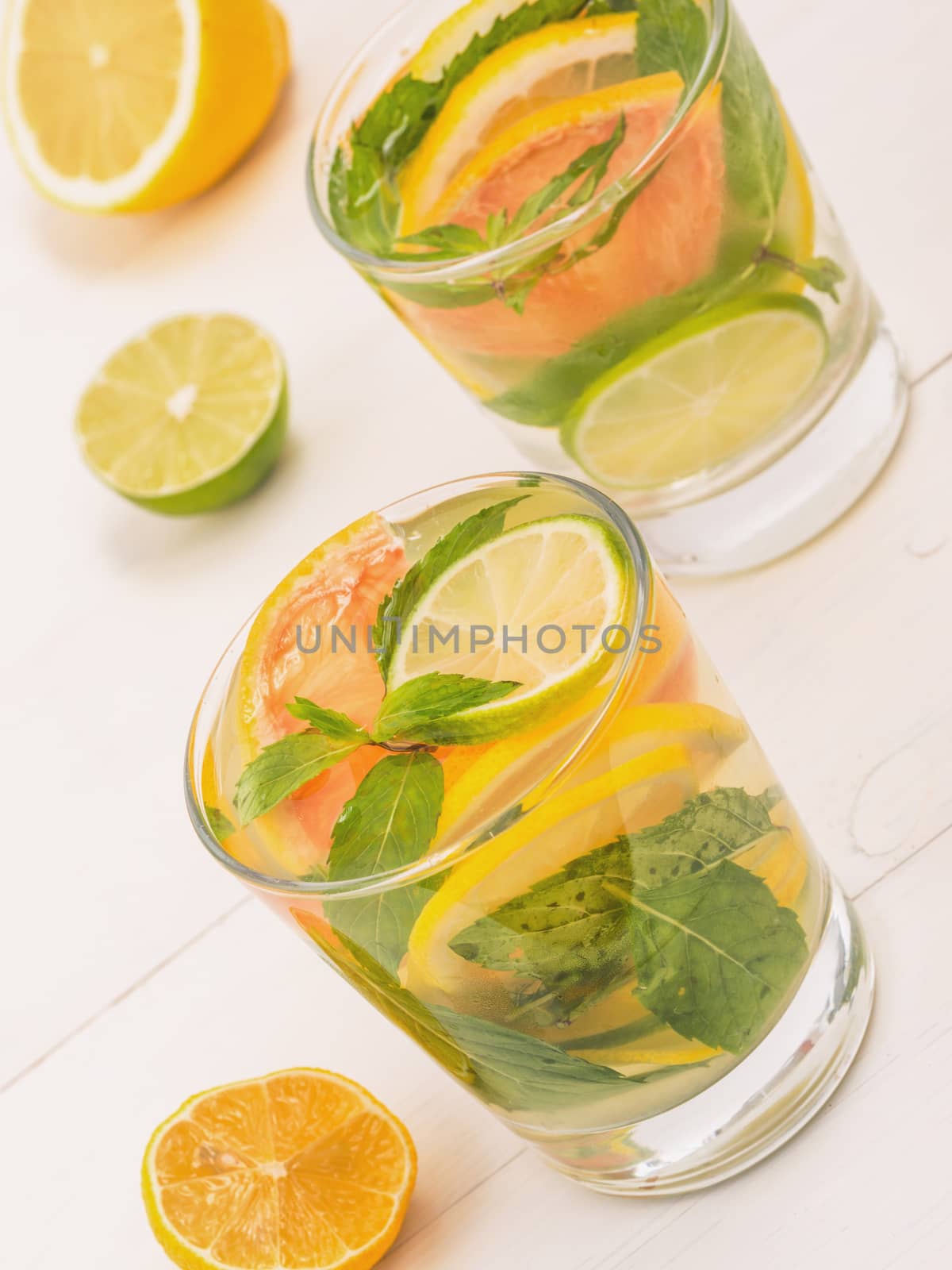 Cold homemade lemonade with fresh lemon, lime, grapefruit and mint. Summer drink on white wooden background