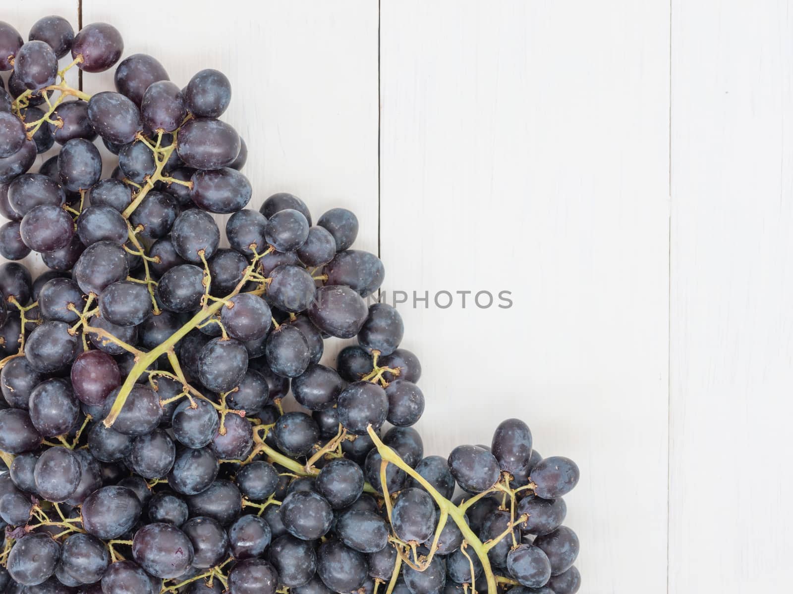 Purple grapes on wooden table by fascinadora