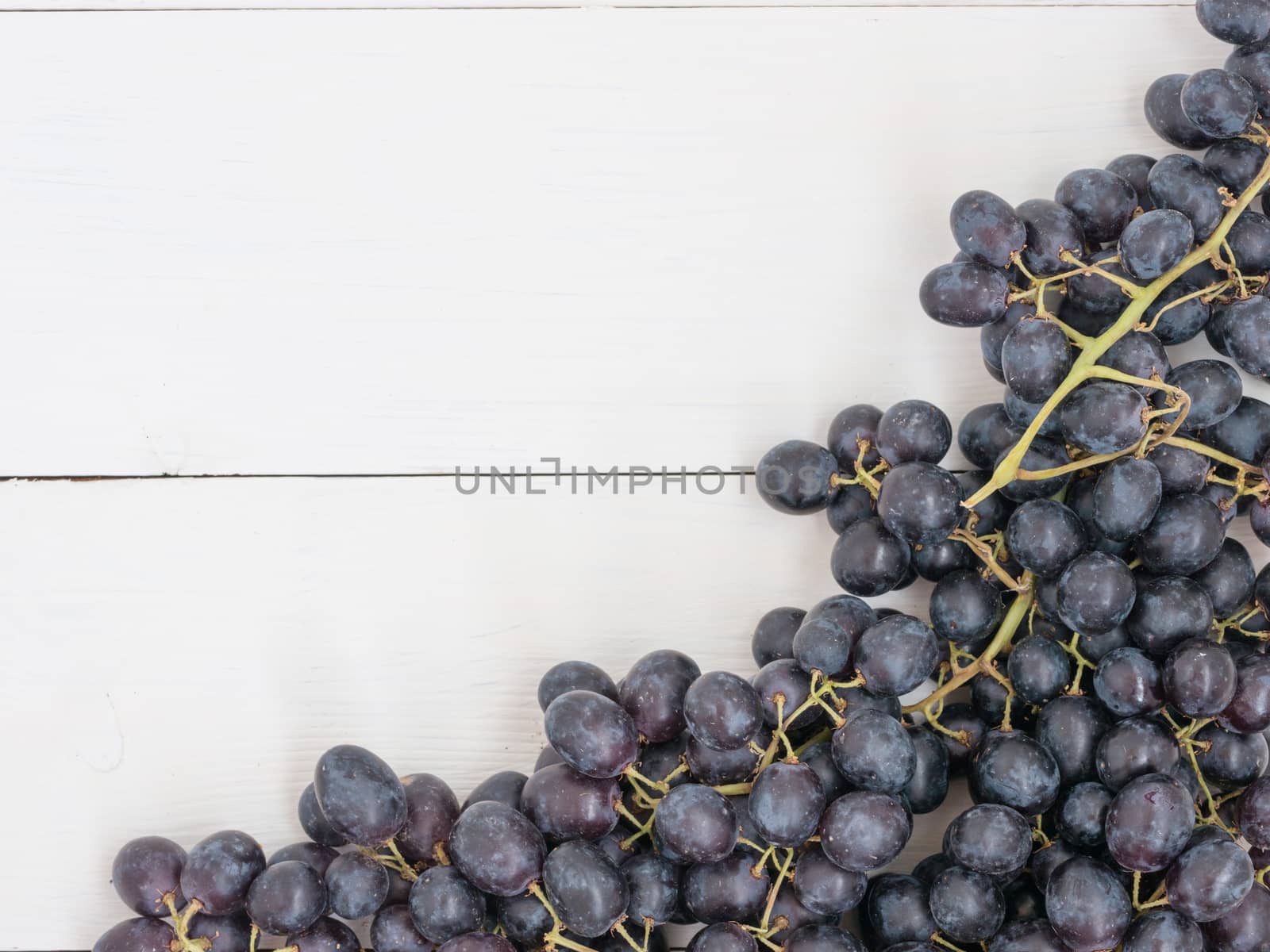 Purple grapes on white wooden table with copyspace. Flat lay or top view