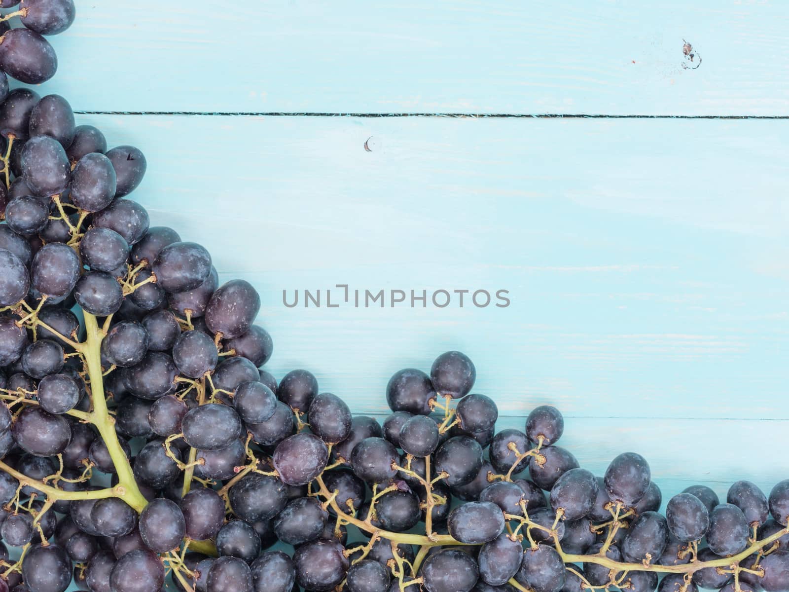 Purple grapes on soft blue wooden table with copyspace. Flat lay or top view