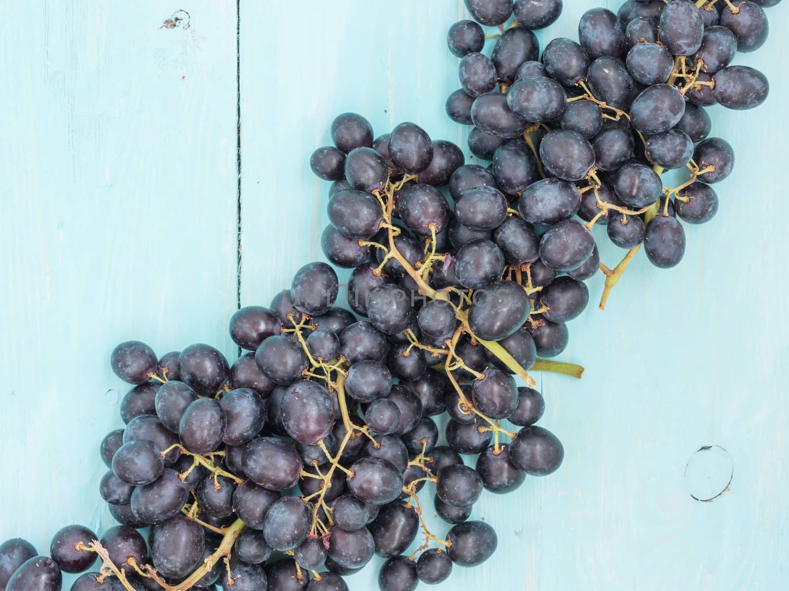 Purple grapes on soft blue wooden table with copyspace. Flat lay or top view