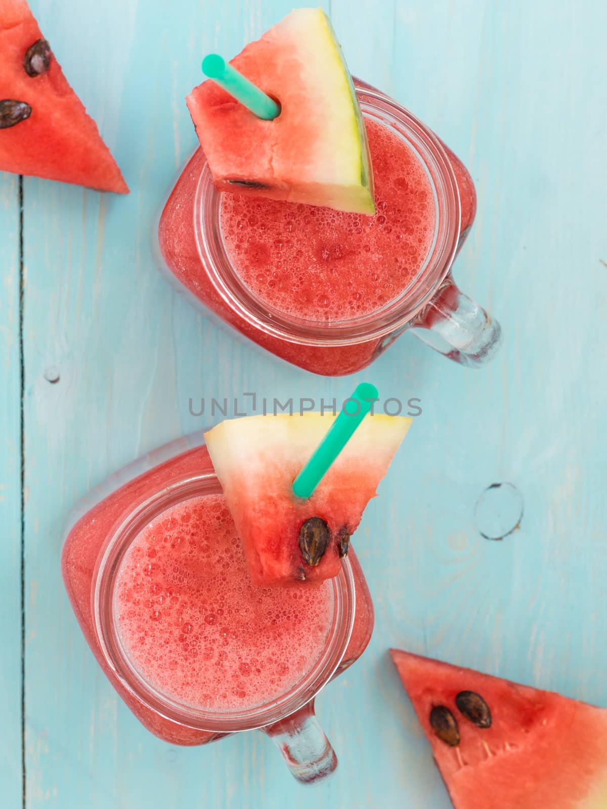 Watermelon smothie and slices on soft blue wooden background. Flat lay or top view. Vertical